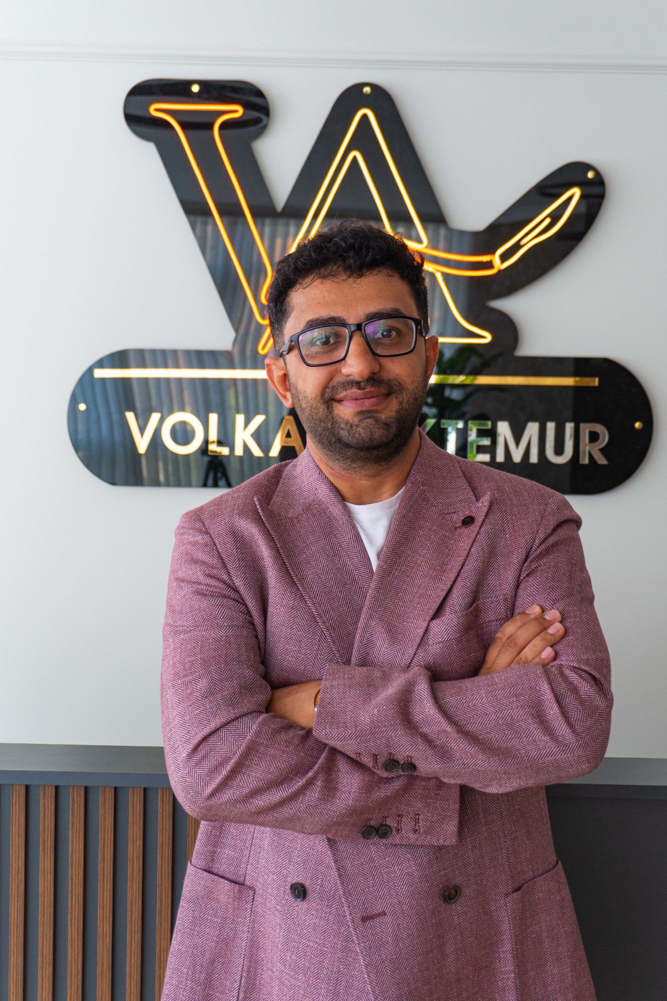 Op. Dr. Volkan Aktemur, muayenehanesinde logolu tabelanın önünde